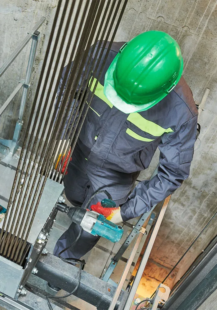 shutterstock_1734810548 A man in a hard hat is working on a ladder.